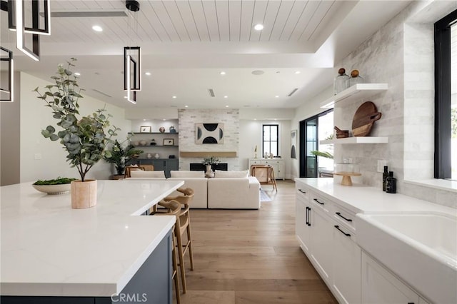 1820 9th St, Manhattan Beach, CA 90266 - kitchen with light wood-style flooring, open shelves, a large fireplace, white cabinets, and decorative light fixtures