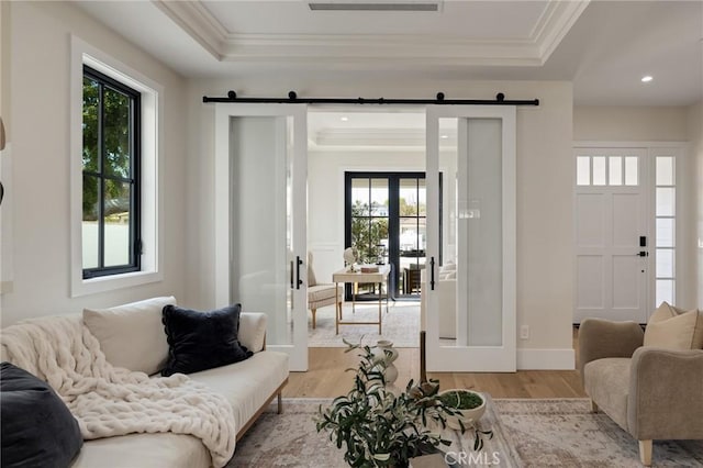 1820 9th St, Manhattan Beach, CA 90266 - living room featuring a barn door, light wood-type flooring, crown molding, and a raised ceiling