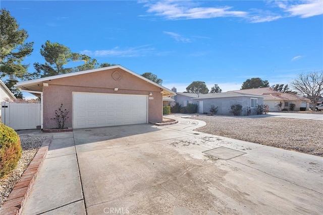 ranch-style home with concrete driveway, an attached garage, fence, and stucco siding