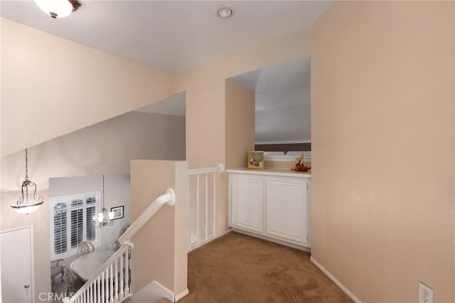 hall with baseboards, light colored carpet, and an upstairs landing