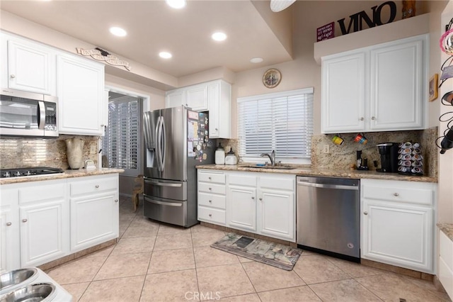 kitchen with light tile patterned floors, appliances with stainless steel finishes, white cabinets, and a sink