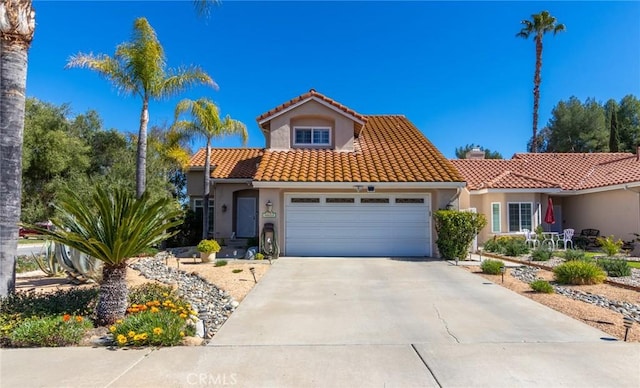 mediterranean / spanish house with a garage, concrete driveway, a tile roof, and stucco siding