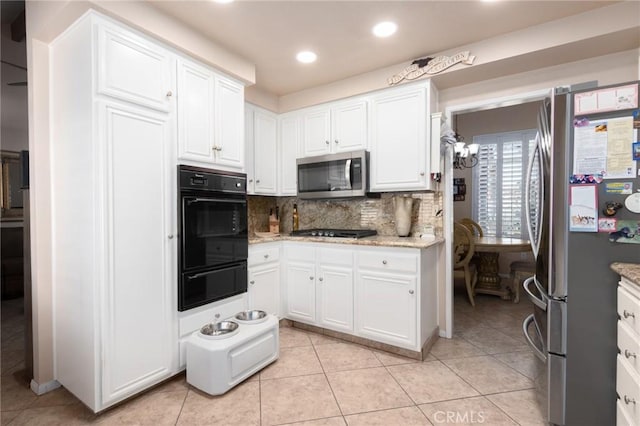 kitchen featuring a warming drawer, appliances with stainless steel finishes, light tile patterned flooring, and white cabinetry