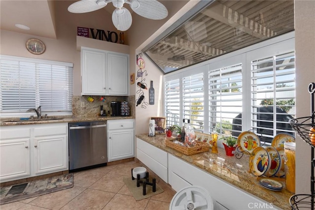 kitchen with light tile patterned floors, backsplash, stainless steel dishwasher, white cabinetry, and a sink