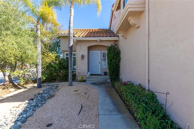 doorway to property featuring a tiled roof and stucco siding