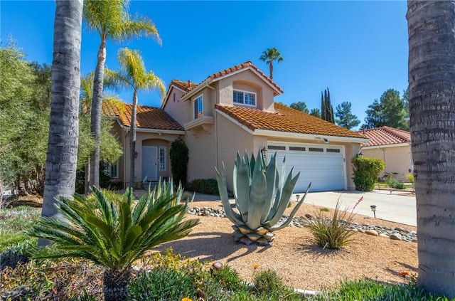 mediterranean / spanish home with a garage, concrete driveway, a tiled roof, and stucco siding