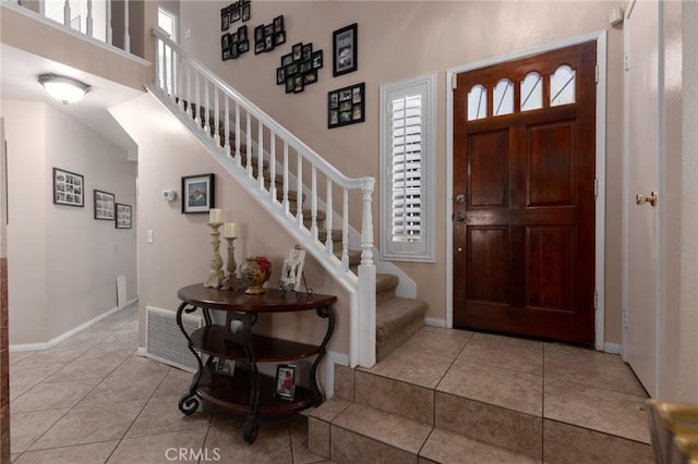 foyer entrance with stairway, light tile patterned flooring, visible vents, and baseboards