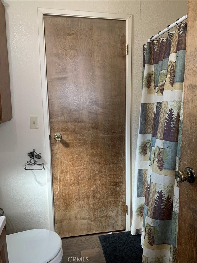 33492 Wild Rose Dr, Green Valley Lake, CA 92341 - full bathroom featuring a textured wall, a shower with shower curtain, wood finished floors, and toilet