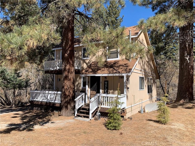 view of front of property with a porch, roof with shingles, and a balcony