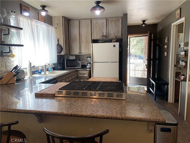 33492 Wild Rose Dr, Green Valley Lake, CA 92341 - kitchen featuring stainless steel microwave, backsplash, freestanding refrigerator, a sink, and a peninsula