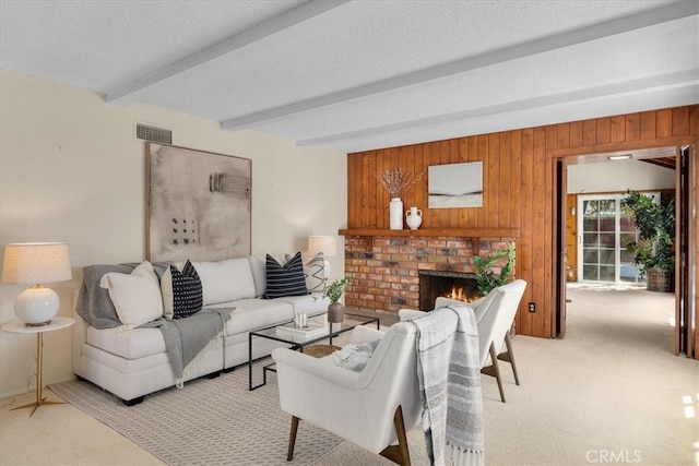 living room featuring a textured ceiling, visible vents, beamed ceiling, and light colored carpet