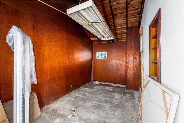 spare room featuring wooden walls and concrete floors