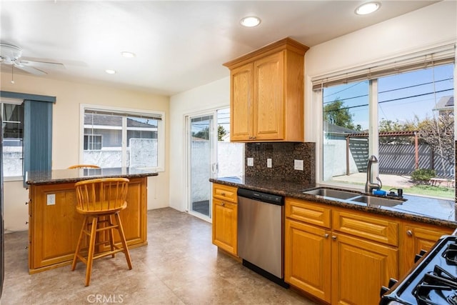 kitchen featuring range with gas stovetop, dishwasher, a breakfast bar area, backsplash, and a sink