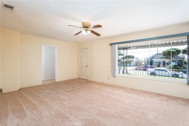 carpeted empty room with visible vents and a ceiling fan