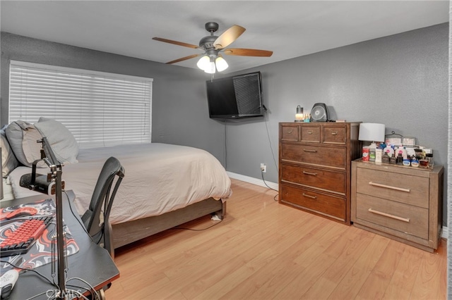 bedroom with light wood-style flooring, baseboards, and a ceiling fan