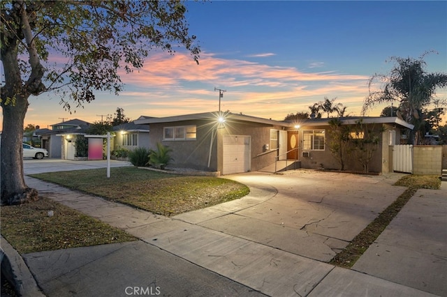 single story home featuring a garage, driveway, a lawn, and stucco siding