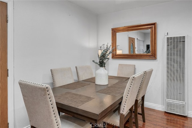 dining room with baseboards, a heating unit, and wood finished floors