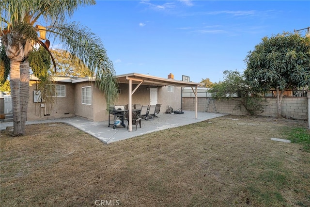 rear view of property with a lawn, a patio area, a fenced backyard, and stucco siding