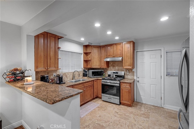 kitchen with stainless steel appliances, stone countertops, a sink, and under cabinet range hood