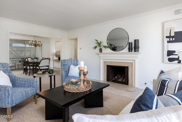 carpeted living room featuring ornamental molding, a premium fireplace, visible vents, and an inviting chandelier