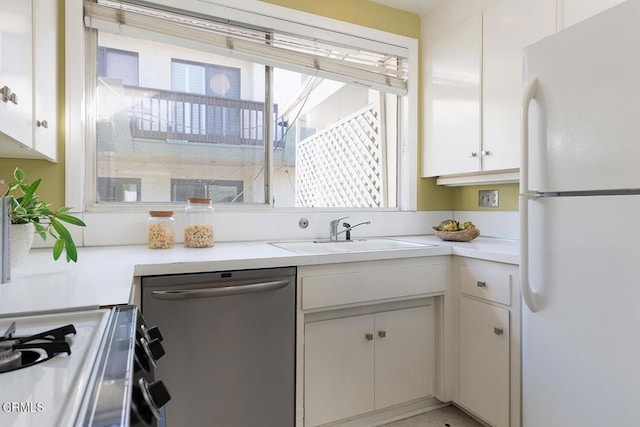 kitchen featuring a sink, light countertops, range, freestanding refrigerator, and dishwasher