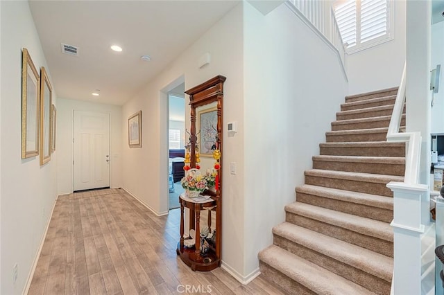 interior space featuring light wood-type flooring, visible vents, stairs, and baseboards