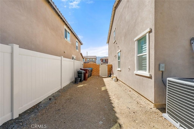 view of side of property featuring fence, cooling unit, and stucco siding