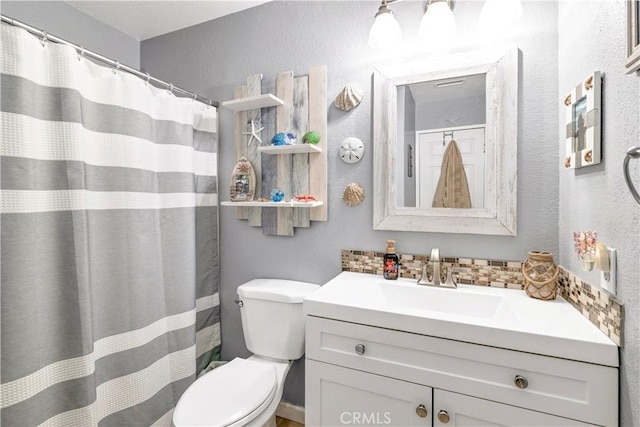 bathroom with a textured wall, vanity, and toilet