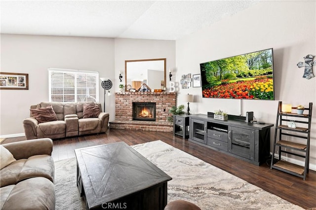 living area with dark wood-style floors, a textured ceiling, and a brick fireplace