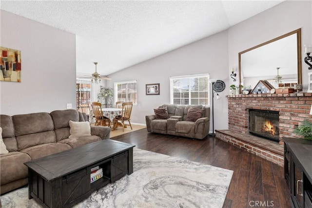 living room with a fireplace, lofted ceiling, ceiling fan, a textured ceiling, and wood finished floors