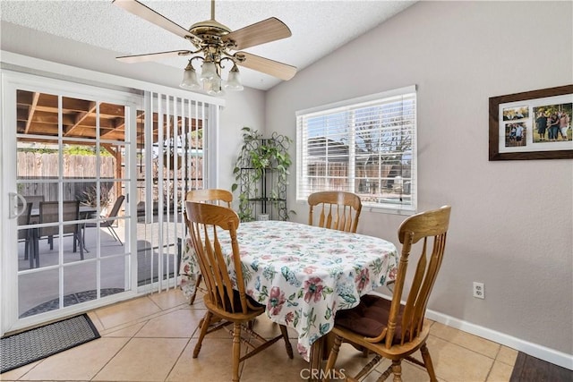 dining area featuring baseboards, a ceiling fan, lofted ceiling, a textured ceiling, and light tile patterned flooring