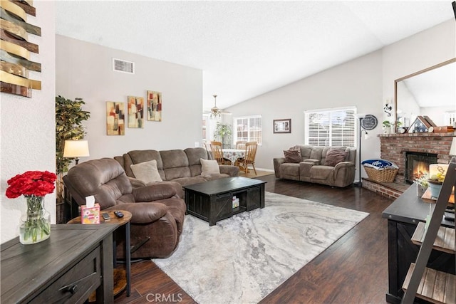 living area with dark wood-style floors, visible vents, vaulted ceiling, and a fireplace