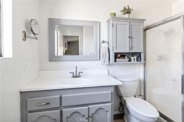 bathroom featuring toilet, a stall shower, and vanity