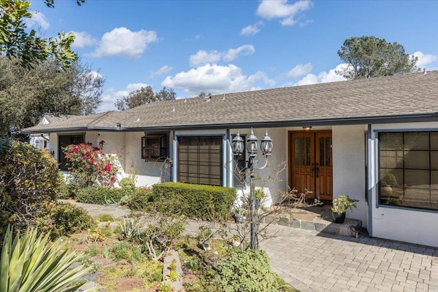 view of front of home with a shingled roof and stucco siding