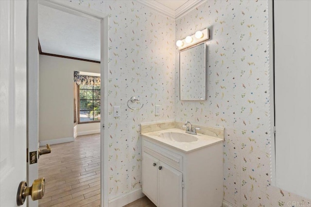 bathroom with crown molding, vanity, baseboards, and wallpapered walls