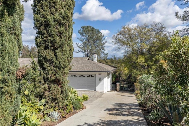 view of property exterior with a garage, a chimney, roof with shingles, fence, and stucco siding