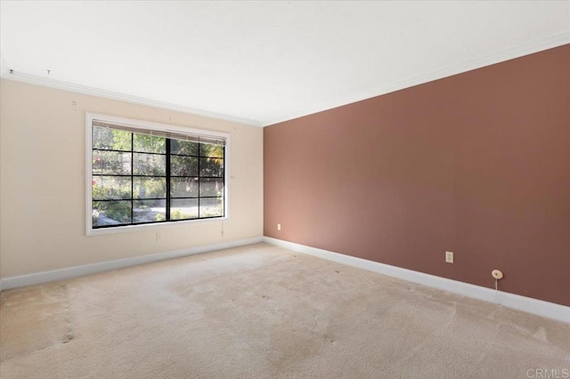 unfurnished room featuring light carpet, baseboards, and crown molding