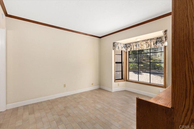 spare room with light wood-type flooring, baseboards, and ornamental molding