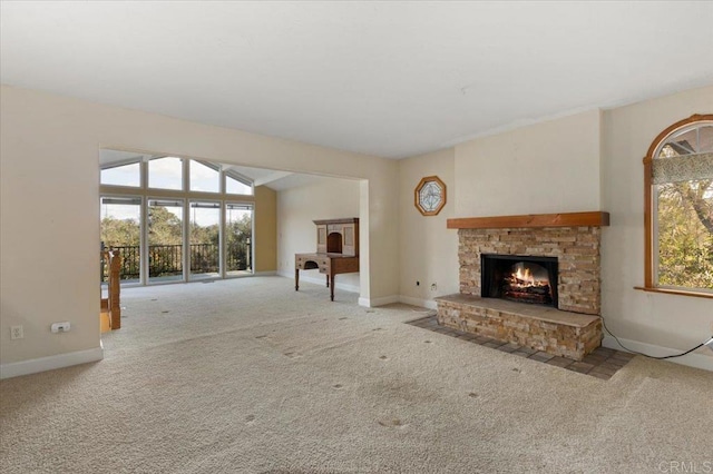 unfurnished living room with carpet, a healthy amount of sunlight, a stone fireplace, and baseboards