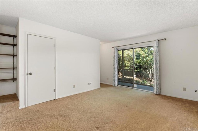 carpeted empty room featuring a textured ceiling