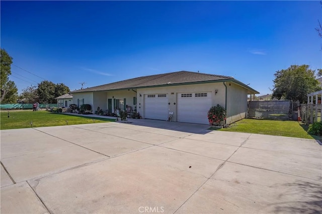 view of front facade with stucco siding, an attached garage, fence, driveway, and a front lawn