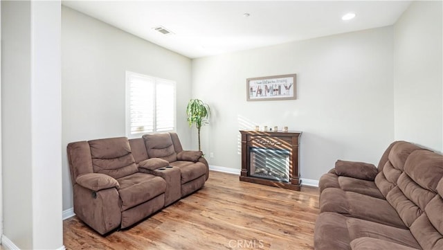 living area featuring light wood-style flooring, recessed lighting, a fireplace, visible vents, and baseboards