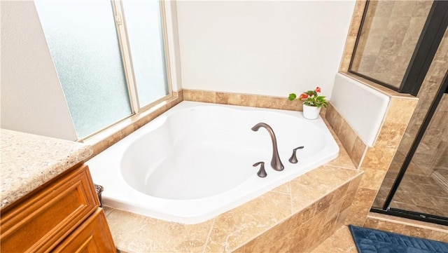 bathroom featuring tiled shower, a garden tub, and vanity