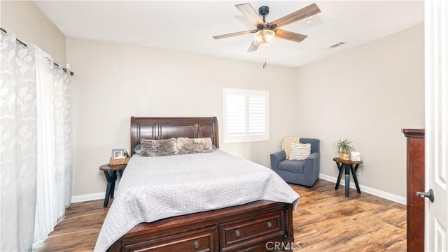 bedroom featuring ceiling fan, light wood-style flooring, visible vents, and baseboards