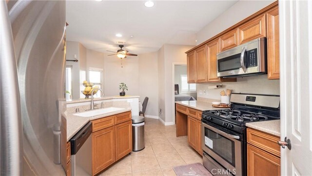 kitchen featuring ceiling fan, stainless steel appliances, light countertops, a sink, and light tile patterned flooring