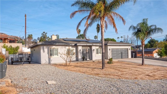 ranch-style home featuring an attached garage, solar panels, fence, concrete driveway, and stucco siding