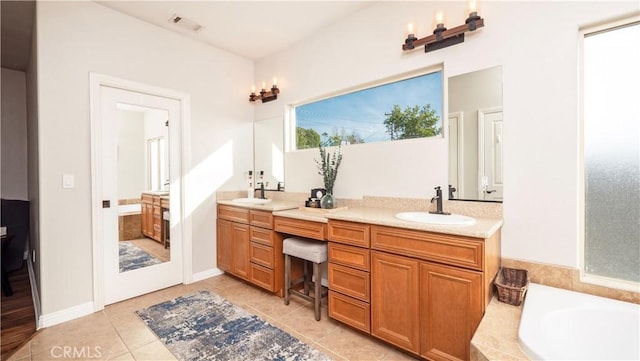 full bathroom with double vanity, a tub to relax in, visible vents, tile patterned floors, and a sink