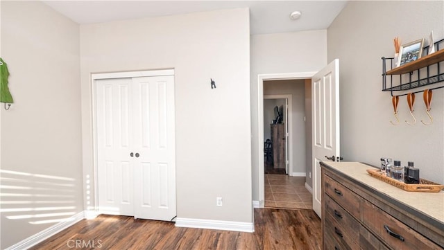 bedroom featuring baseboards, dark wood-type flooring, and a closet