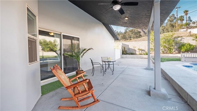 view of patio / terrace with fence, a ceiling fan, and an outdoor pool