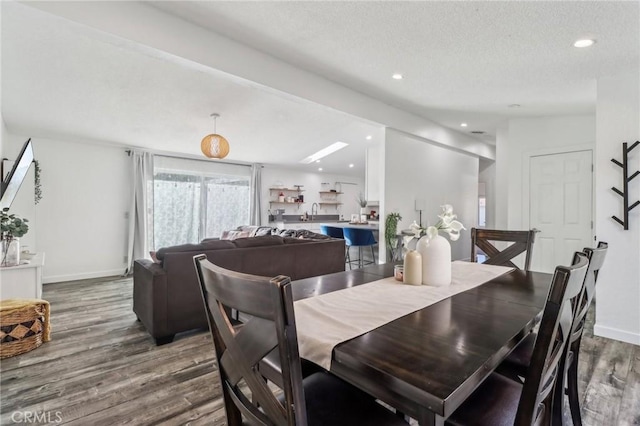 dining space featuring a textured ceiling, baseboards, wood finished floors, and recessed lighting